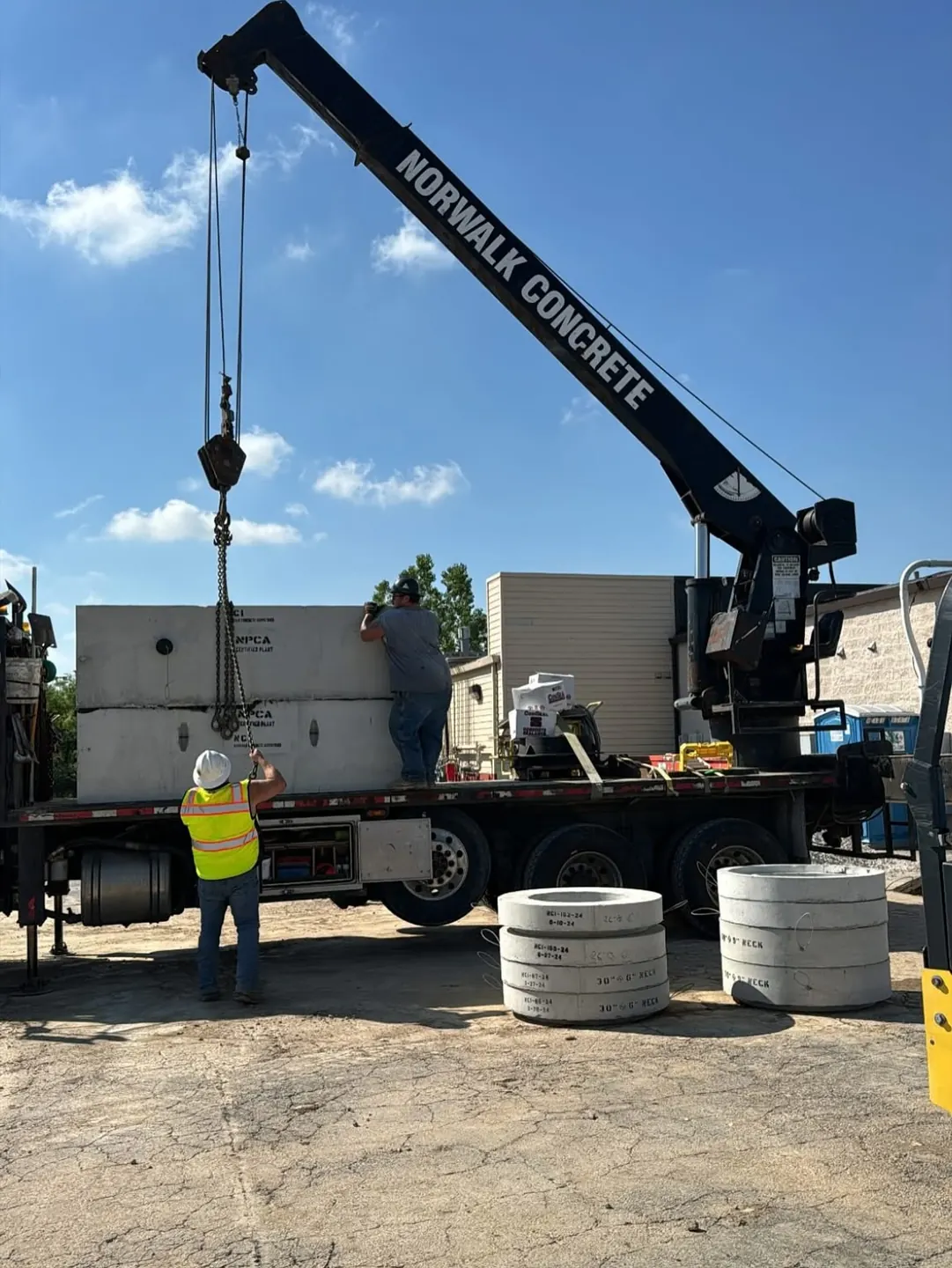 Crane crew handling precast concrete structures at a commercial work site