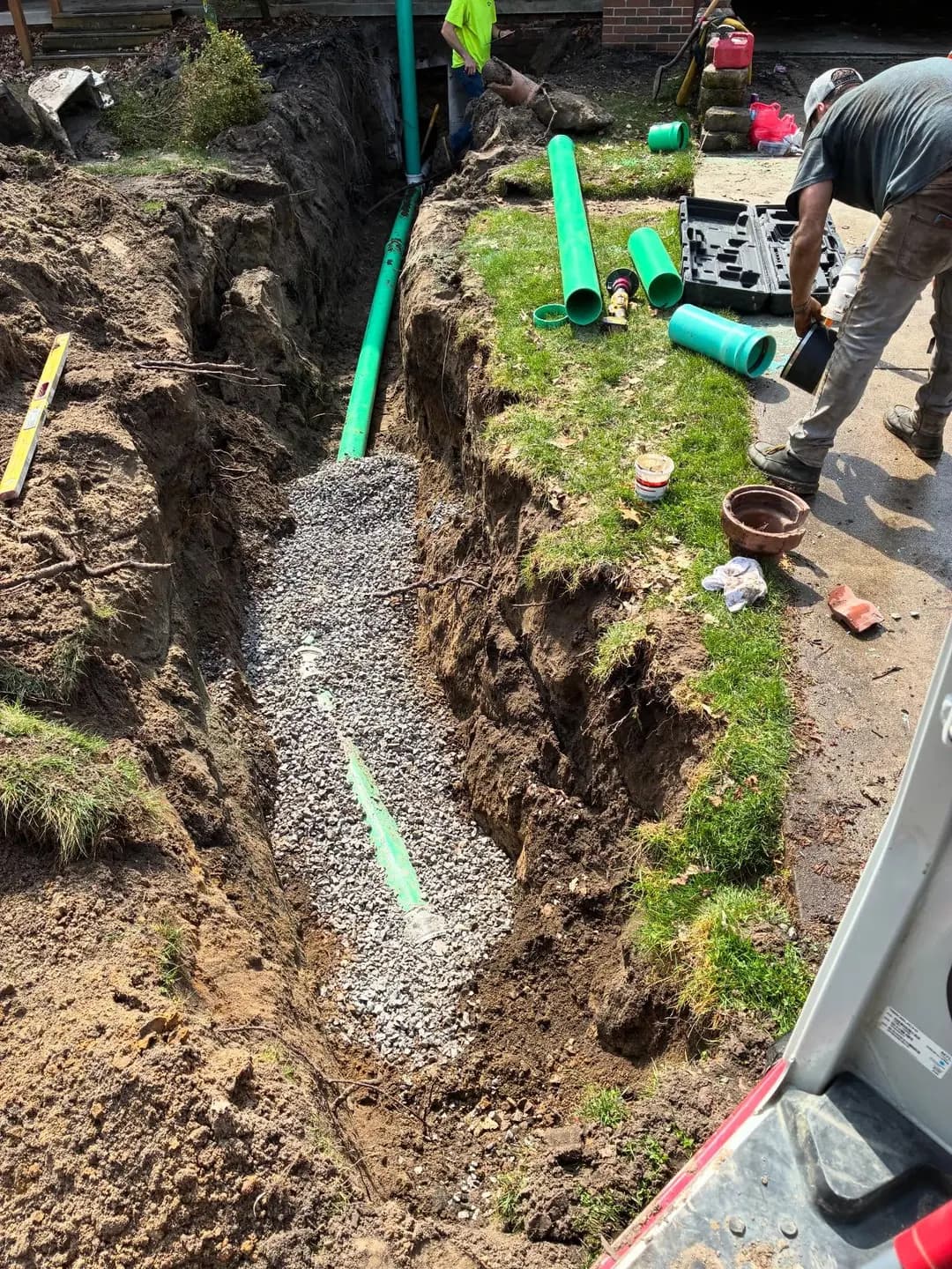 Green sewer pipe being installed in an open residential trench
