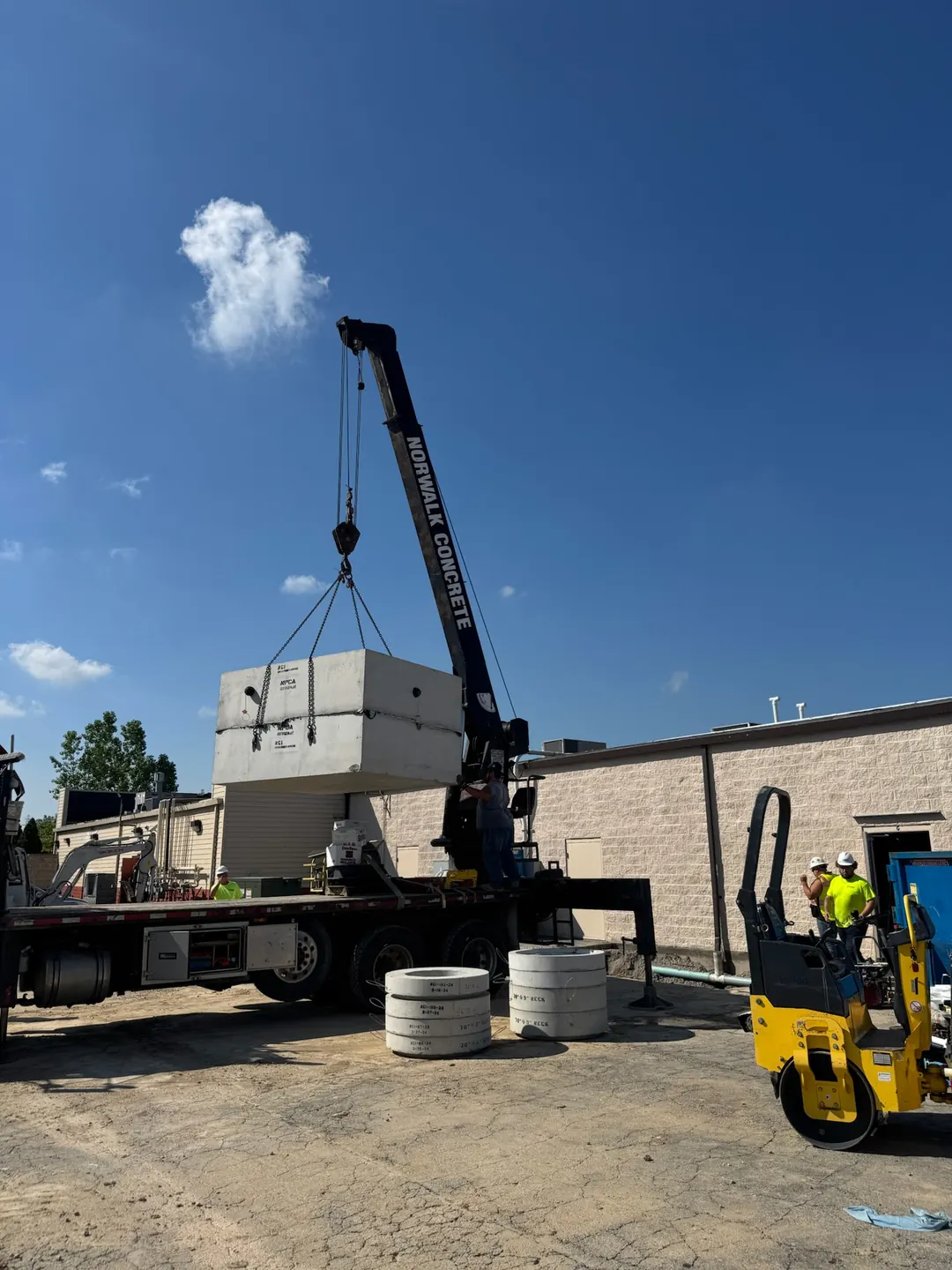 Crane and crew positioning a precast concrete drainage structure